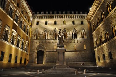 Low angle view of statue amidst historic building at night