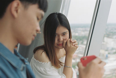 Portrait of a young woman looking through window