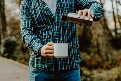 Midsection of man pouring coffee in cup
