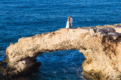 High angle view of woman standing on rock by sea