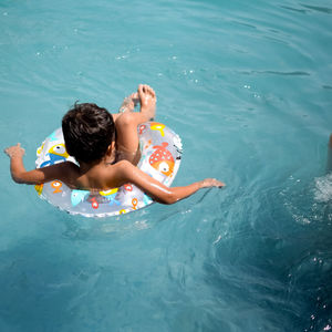 Happy indian boy swimming in a pool, kid wearing swimming costume along with air tube