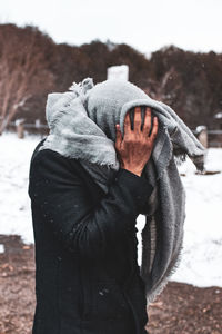 Man with shawl covering head while standing outdoors during winter