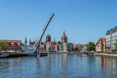 River amidst buildings in city against clear blue sky