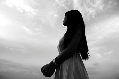 Low angle view of young woman against sky