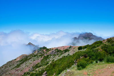 Scenic view of land and mountains against blue sky