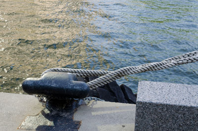 Close-up of ropes at bollard against water