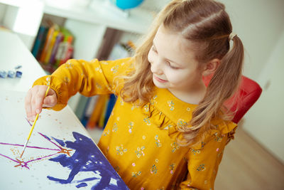 Girl painting on paper at home