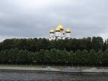 View of trees by building against sky
