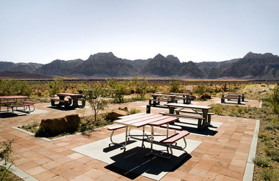Chairs and table by swimming pool against sky