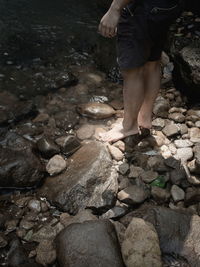 Low section of woman standing on rock at shore