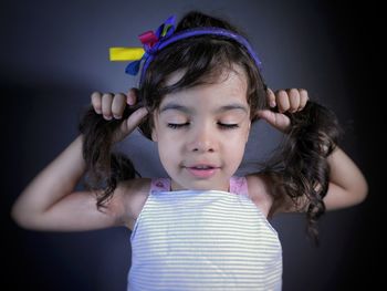 Close-up of cute girl holding ponytails by wall