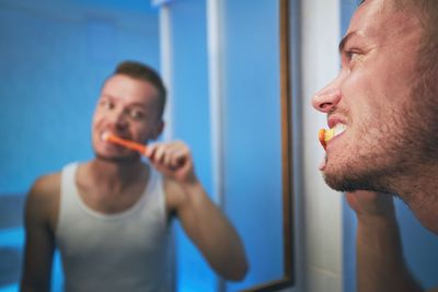 Portrait of man with arms raised in bathroom