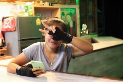 Young woman using mobile phone while sitting on table