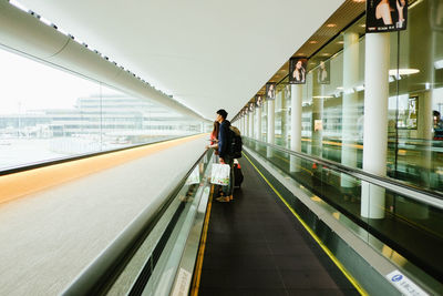 Rear view of man walking on illuminated bridge