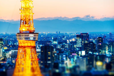 Illuminated buildings in city against sky at sunset