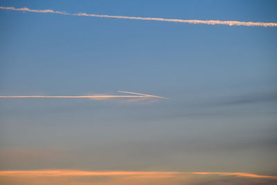 Low angle view of vapor trails in sky during sunset