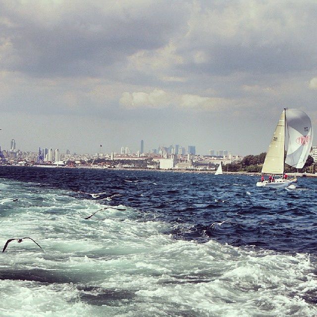 water, sea, nautical vessel, sky, waterfront, transportation, built structure, architecture, building exterior, city, mode of transport, cloud - sky, boat, sailing, rippled, wave, cloudy, ship, cloud, travel