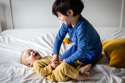 Two small smiling children in bright clothes playing on the parent's bed