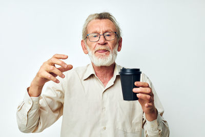 Portrait of young woman drinking glass against white background