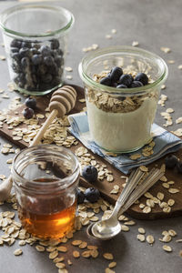 High angle view of oats and blueberries with yogurt in jar by maple syrup on table