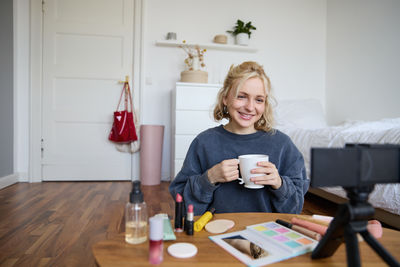 Portrait of young woman sitting on sofa at home