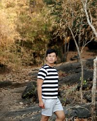 Portrait of mid adult man standing against trees in forest