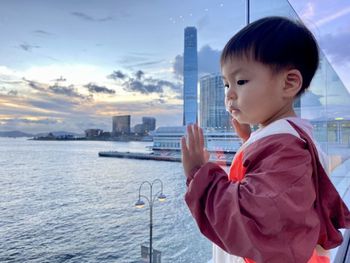 Side view of asian boy looking at sea against sky