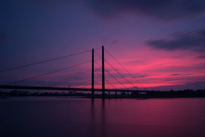 Bridge over river against sky at sunset