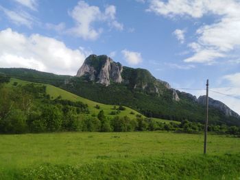 Scenic view of green landscape and mountains against sky