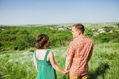 Couple holding hands while standing in forest
