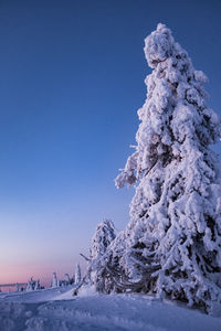 Snow covered landscape against clear blue sky