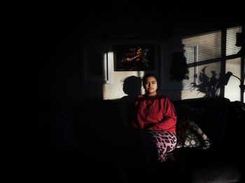 Young woman sitting on sofa at home