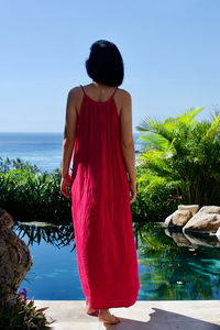 Rear view of woman standing on beach against sky