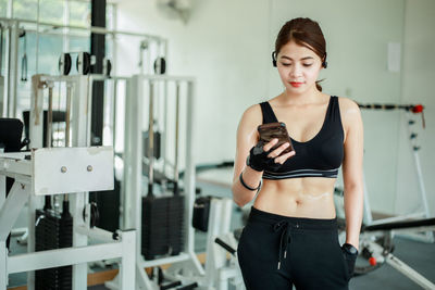 Beautiful young woman using mobile phone in gym