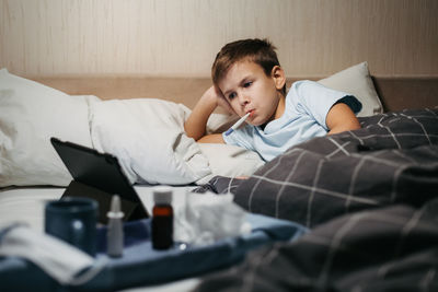 Young woman using mobile phone while lying on bed at home