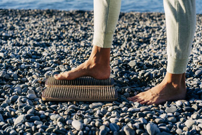Barefoot female foot stands on a wooden board with nails for concentration practice by seashore