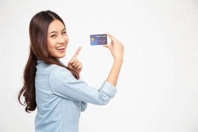 Portrait of smiling young woman using phone against white background