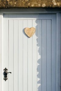 Wooden heart shape decoration hanging on closed white door