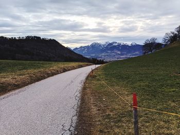 Road leading towards mountains against sky