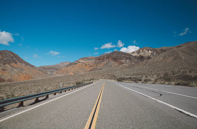 Empty road by mountains against sky