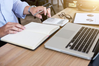 Cropped image of businessman using calculator at desk in office