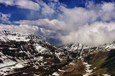 Snow covered mountains against cloudy sky