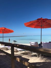 Lounge chairs on beach against clear blue sky