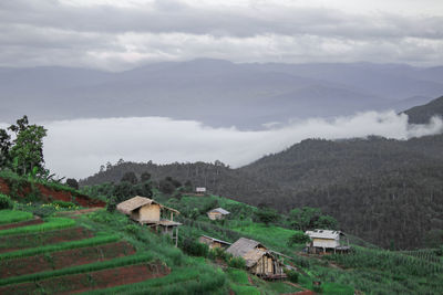 Houses on field by mountains against sky