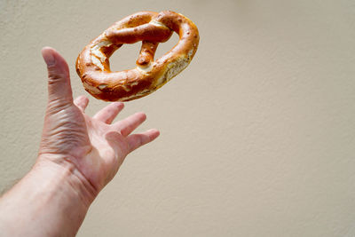 Cropped image of hand reaching for pretzel against wall