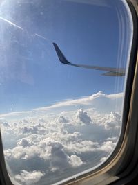 Airplane flying in sky seen through glass window