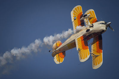 Low angle view of biplane flying against sky