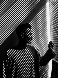 Sunlight streaming through window blinds on man