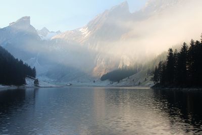 Scenic view of lake by snowcapped mountains against sky
