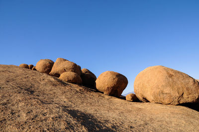 View of rocks against clear blue sky